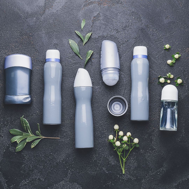 šedivé lahvičky od antiperspirantů, kolem jsou květiny