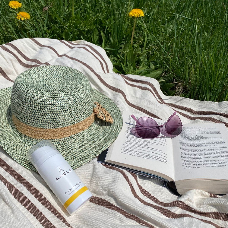 kniha, brýle, klobouk a opalovací krém na dece