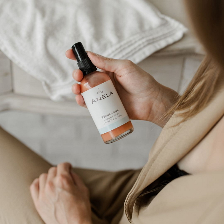 ženská ruka držící lahvičku hydratačního séra Růžové z nebe