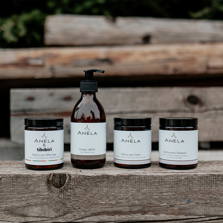 čtyři kosmetické produkty vhodné pro ekzematickou pokožku, postavené na dřevěné kládě